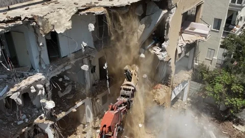 Drone shot capturing the destruction of a building by a massive bulldozer Stock Footage 294723142