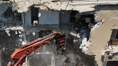 Drone shot capturing the destruction of a building by a massive bulldozer Stock Footage 294723149