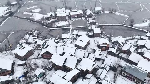 Drone shot capturing tranquil snowfall over wooden homes floating on Dal Lake in Stock Footage 310223199