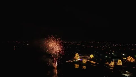 Drone shot capturing vibrant fireworks during a festive event over a lakeside Stock Footage 334675622