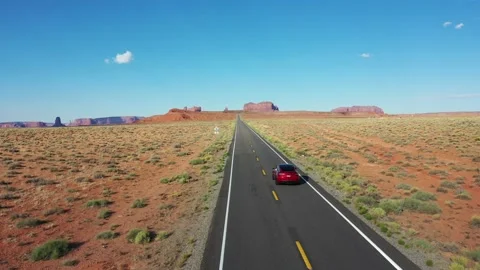 Drone shot of a car driving on State Route 163 in Utah toward Monument Valley Stock Footage 229518586