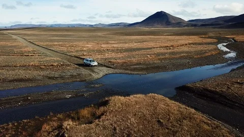 Drone shot of car driving through the water stream towards road Stock Footage 120420463