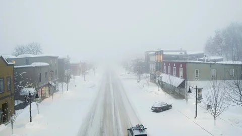 Drone shot of car driving through town covered in snow during misty day, Canada Stock Footage 121585774