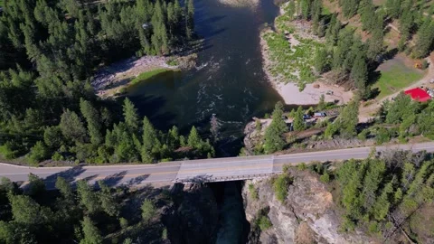Drone shot of a car passing over a highway bridge spanning over a wild river Stock-Footage 339074236