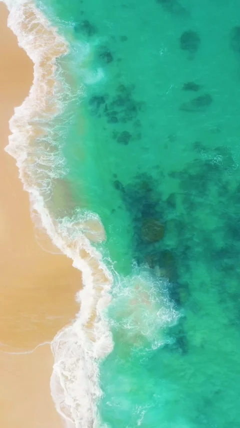 Drone Shot Of Clean Sandy Beach With Bright Emerald Green Sea In Vertical Format Stock Footage 346946611