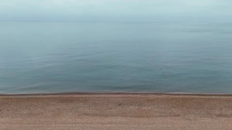 Drone shot of Coastline on a calm cloudy day, with stone beach and soft waves Stock Footage 330907458