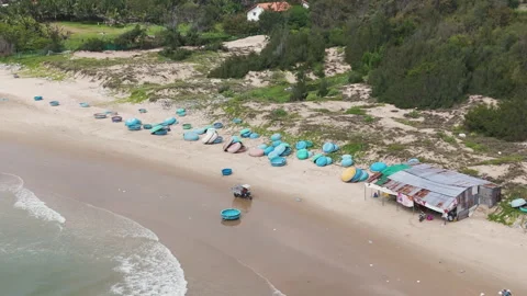 Drone shot of coracle boats lining the beach as waves crash in Mui Ne Stock-Footage 252632491