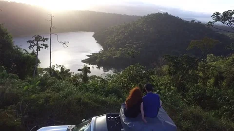 Drone shot of couple looking across lake at sunset Stock Footage 74401428