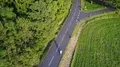 Drone shot cyclist on mountain road at woodland grass meadow 4k or 4k+ Resolution