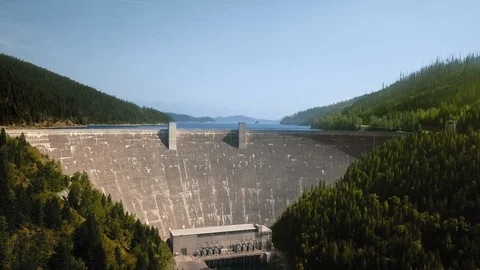 Drone shot of a dam in front of a river between wooded mountains Video stock 123392606