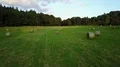 Drone shot deep flight over rolled corn field hay bales on woodland grass meadow 4k or 4k+ Resolution