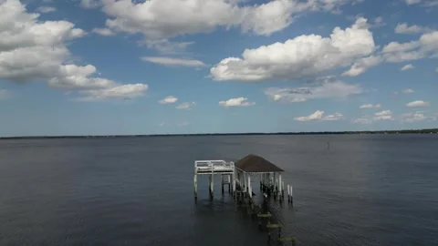 Drone shot of derelict river dock with blue skies with clouds Vídeo Stock 244090189