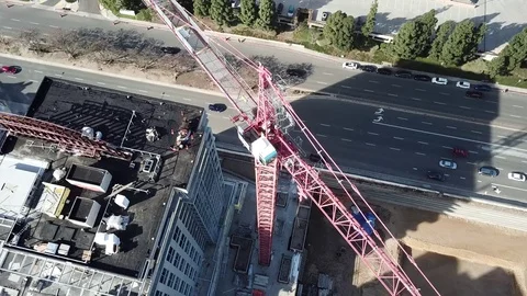 Drone shot descends from top of crane near building under construction Stock Footage 84949016