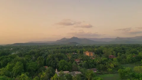 Drone shot of Devrukh village amid lush greenery, mountains &amp; dramatic clouds Video stock 304490971