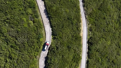 Drone shot directly above a red and white cargo truck navigating steep curves Vídeo Stock 331098495