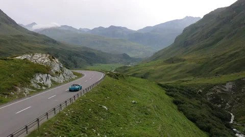 Drone shot dive into a sport car in the roads of Switzerland. Stock Footage