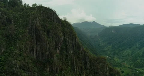 Drone shot of dramatic mountain cliff with fog flowing through valley 스톡 동영상 333407866