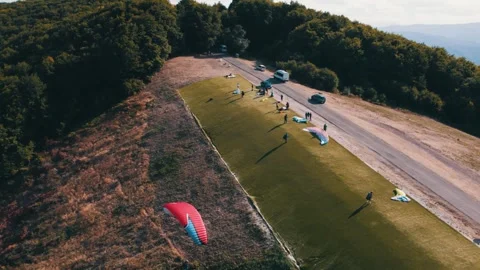 Drone shot of an expert paragliding pilot flying off into the air. Extreme Video stock 266903916