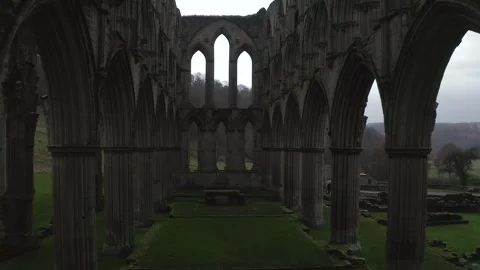 Drone shot exploring the historical Rievaulx Abbey ruins surrounded by lush 動画素材 296761013