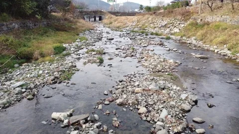 Drone shot featuring riverbanks with rocks and flowing wate 動画素材 250944937