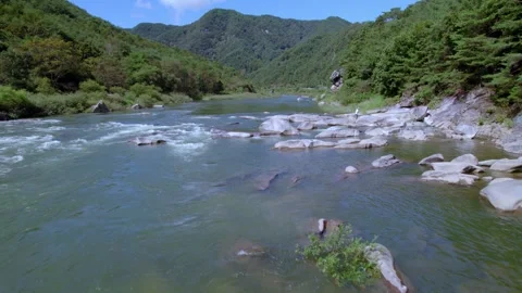 Drone shot featuring riverbanks with rocks and flowing wate Stock Footage 251410409