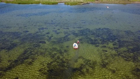Drone shot of fisherman pulling his boat in shallow sea Stock Footage 87689475