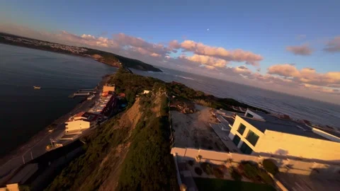 Drone shot flies over hillside town beside ocean at sunset Stock Footage 344577850