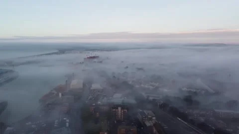 Drone shot flying above low cloud as buildings in the town below peak through Stock Footage 341897357