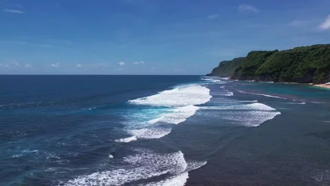 Drone shot flying backwards over ocean waves, green hills and blue sky Stock-Footage 248756782