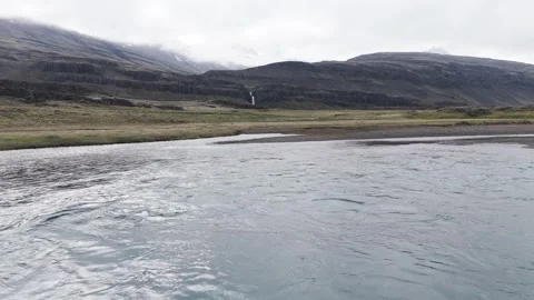 Drone shot flying beneath bridge over river and towards a waterfall, Iceland. 4K Stock Footage 279676958