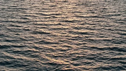 Drone shot flying low over calm sea at sunrise with bright reflections and .. Stock Footage 316888341