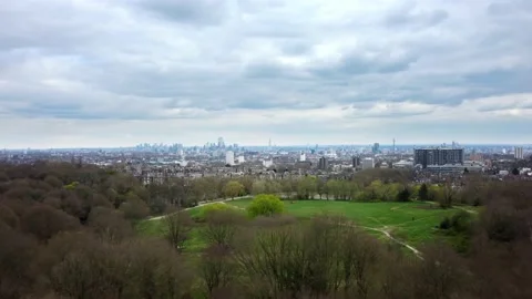 Drone shot flying over Hampstead Heath park with London in backdrop Stock Footage 175690905