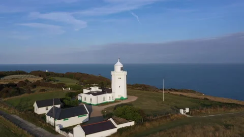 Drone shot flying over a lighthouse to reveal countryside and the sea. 4k Stock Footage 147367132