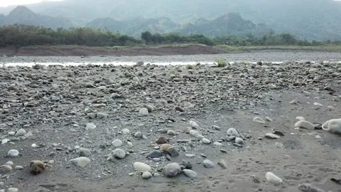 Drone shot flying over rocks, river with mountains in the background (Taiwan) Stockbeeldmateriaal 329052254