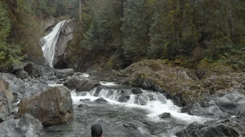 Drone shot flying over young hiker woman to reveal waterfall, 4K Stock Footage 169475708