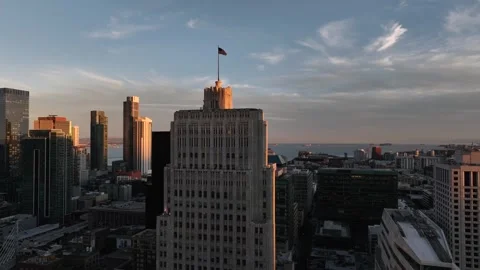 Drone shot flying toward American flag on skyscraper rooftop of sunset cityscape Stock Footage 301042296