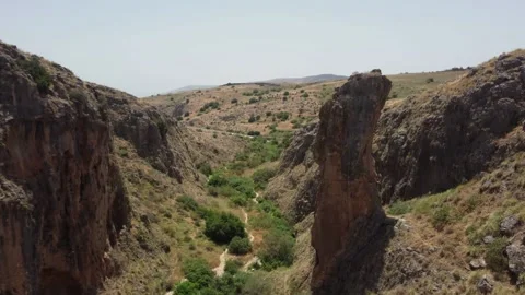 Drone shot flying towards a distinctive rock pillar in a desert canyon. Stock Footage 154753578