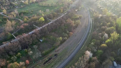 A drone-shot of a freight train crossing a viaduct through a city, surround.. Video stock 239733836