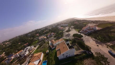 Drone shot glides over sandy dunes, seaside houses, and calm ocean waves Stock Footage 345059595