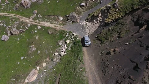 Drone shot from great height of multiple suv driving through convoluted mountain Stock Footage 171921254