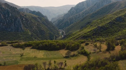 Drone shot of a green valley with river and mountains in the background 4k Stock Footage 105924120