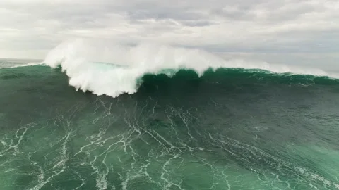 Drone shot of huge ocean wave with surfers and jet ski drivers near Stock Footage 163286599