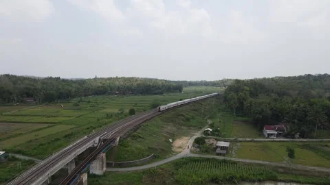 Drone shot, Indonesian train passing through a double track railway bridge Stock Footage 291844679