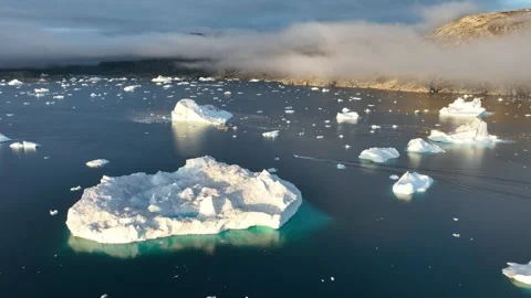 Drone shot of Inuit boat passing by icebergs in a large fjord of East Greenland Stock Footage 332371953