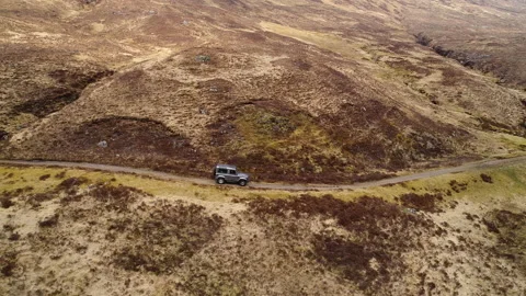 Drone shot of Landrover Defender through Scottish hills on a off road path Stock Footage