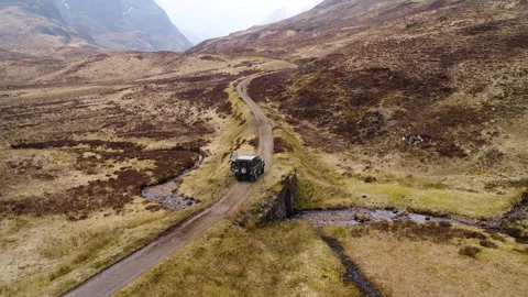 Drone shot of Landrover driving through Scottish hills Stock Footage