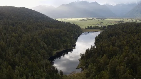 Drone shot large reflective river cutting through forest Stock Footage 86534493