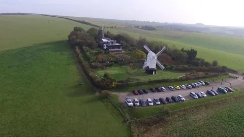 Drone shot looking down on a windmill on a tall hill above the English Stock Footage 343899690