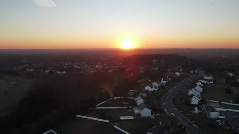 Drone shot lowering down on a sunset over a quiet suburban neighborhood slow Stock Footage 228699474