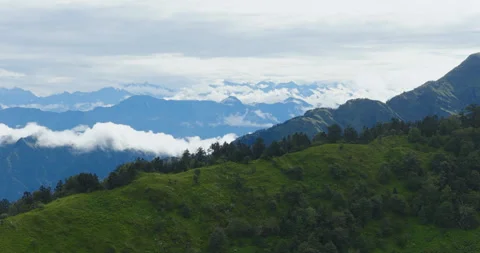 Drone shot of lush green forest ridge, distant mountain ranges and cloud in Vídeos de archivo 346340339
